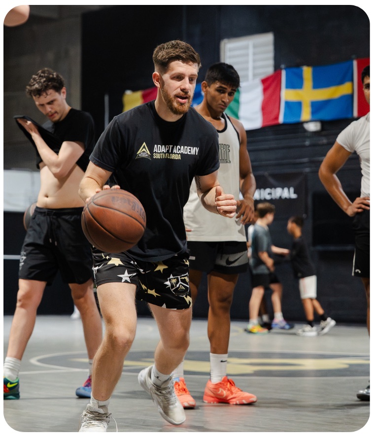 Coleman Ayers coaching in a gym lined with national flags
